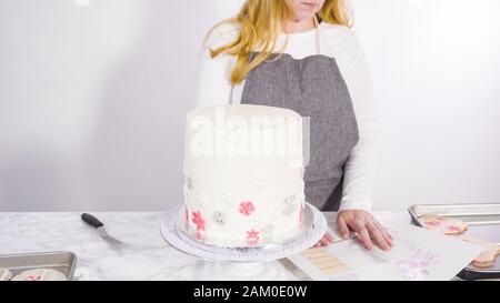 Einfügen von großen Lutscher mit Schneeflocken in den hohen Weiße, runde Kuchen als Dekoration. Stockfoto