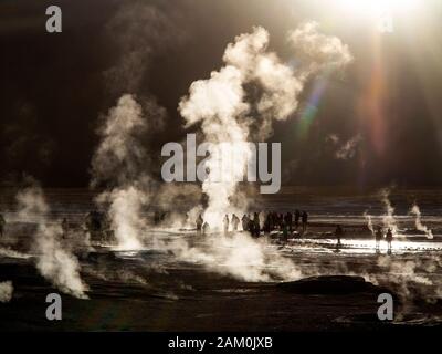 Touristen, die in der berühmten Geiser del Tatio bei Sonnenaufgang, Atacama-wüste, Chile Stockfoto