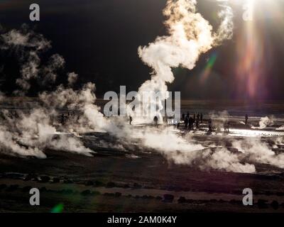 Touristen, die in der berühmten Geiser del Tatio bei Sonnenaufgang, Atacama-wüste, Chile Stockfoto