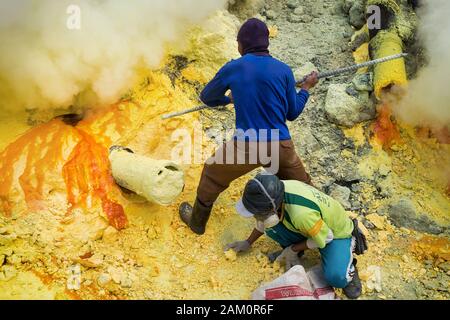 Schwefel-Minenarbeiter, die Schwefel am Krater des Kawah Ijen Vulkans in Ostjava, Indonesien, gewinnen. Stockfoto