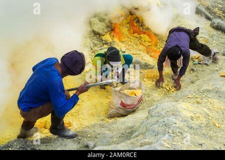 Schwefel-Minenarbeiter, die Schwefel am Krater des Kawah Ijen Vulkans in Ostjava, Indonesien, gewinnen. Stockfoto