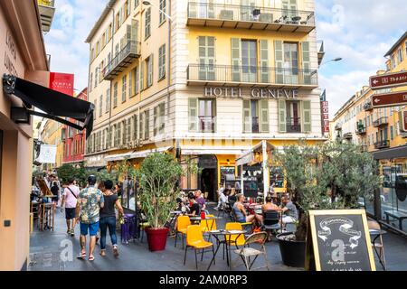 Touristen kommen an Hotels, Cafés und Geschäften in der Altstadt von Nizza, Frankreich, an der französischen Riviera vorbei. Stockfoto