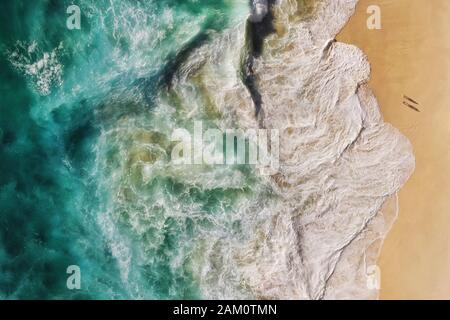 Luftaufnahmen von türkisblauen Meereswellen, die am Ufer des unberührten, abgeschiedenen Strandes in Bali, Indonesien, aufbrechen. Stockfoto