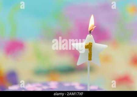 Beleuchtete Geburtstagskerze in Sternform mit verschwommenem Hintergrund. 1 Jahr Jubiläum, Tiefseethema. Celebration, Party und Joy Konzept. Stockfoto