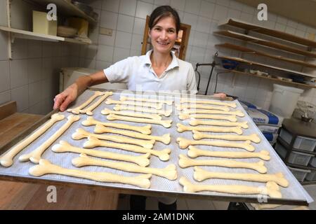 Irsee, Deutschland. 08 Jan, 2020. Gudrun Koneberg, Bäckermeister, hält ein Backblech mit Lauge Gebäck in der Form eines Knochen in die Bäckerei ihrer Bäckerei. Die Bäckerei ist in der Nähe von dem Ort, wo die Gebeine der Primas Udo, die etwa 11,6 Millionen Jahre alt sind, gefunden wurden. (Dpa: "Nachrichten von den Great Ape Udo - Die Primaten sind jetzt verfügbar als Brezeln') Credit: Karl-Josef Hildenbrand/dpa/Alamy leben Nachrichten Stockfoto