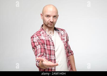 Selbstbewusster Mann gibt Hand für Handschlag und schaut mit einem ernsthaften Gesichtsausdruck auf die Kamera. Stockfoto