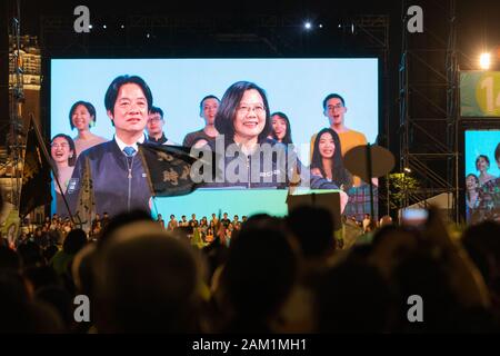 Die Menschen jubeln und Wave Flags als Taiwan Präsident Tsai Ing-wen und ihre vizepräsidentenanwärter William Tsai auf einem Bildschirm hinter ihnen auf der Bühne ihre Ketagalan Boulevard Wahl Rally erscheinen am 31.01.10, 2020, dem Vorabend von Taiwan die Präsidentenwahl 2020., Taipei, Taiwan, 10. Januar 2020 durch Perry Svensson Stockfoto