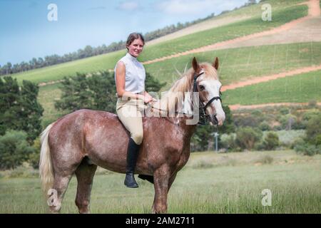 Portrait eines Mädchens, das auf ihrem Sabino-Malpferd auf dem Feld spaziert und die Kamera bareback und ohne Zaum betrachtet. Stockfoto