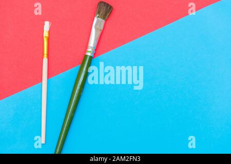 Rot-blaue Kunst Flachlay-Konzept mit grünen und weißen Pinsel, die Kreativität, Inspiration und künstlerischen Ausdruck illustrieren. Stockfoto