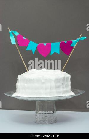 Weißer Vanillegeburtstich mit Festbanner. Grauer Hintergrund. Celebration Concept Stockfoto