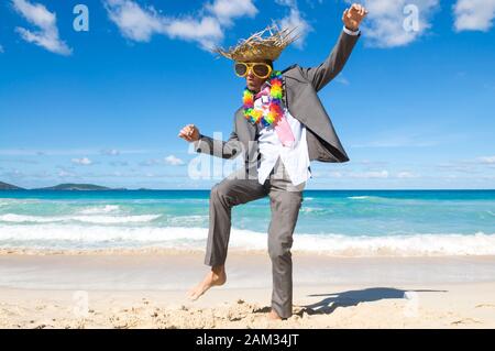 Tanzen Geschäftsmann Sonnenbrillen tragen, touristische Strohhut und lei Feiern auf einem tropischen Strand Stockfoto