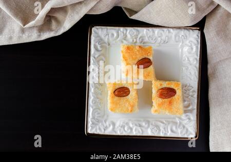 Drei Stücke Basbousa Traditionelle arabische Semolina Kuchen mit Nüssen Orange Blossom Wasser Vertikal Kopieren Raum Dunker Hintergrund Stockfoto