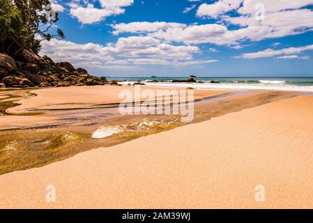 Der Bach fließt über den Strand von Whiritoa, Waikato, North Island, Neuseeland Stockfoto