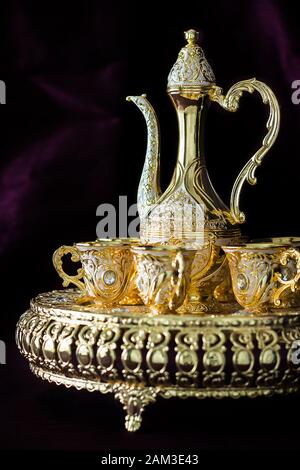 Stillleben Traditionelles arabisches goldenes Kaffee-Set mit dallah. Dunkler Hintergrund. Vertikales Foto Stockfoto