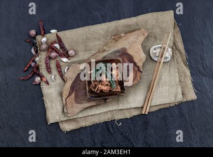 Thailändisches Würziges Essen, Würziges Rühren gebratenes Tiefes Fischfilet mit Kräutergemüse in Holzschale: In thailändischer Sprache "Pad Cha" genannt. Draufsicht. Stockfoto