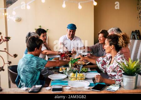 Familien mischten Generationen, die zu Hause oder im Restaurantkonzept gemeinsam zu Mittag essen - junge Erwachsene und ältere Männer und Frauen mit Essen auf dem Tisch - kein Techon Stockfoto