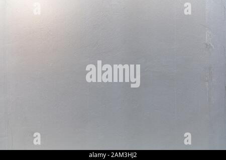 Die Wand ist grau lackiert und hat einen grauen Hintergrund und eine Struktur. Stockfoto