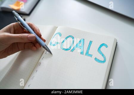 Hohe Betrachtungswinkel der Kaufmann Hand schreiben das Ziel das Konzept die auf Notebook Stockfoto