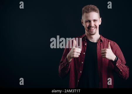 Lächelnden jungen Mann mit Bart Daumen zeigt nach oben Stockfoto