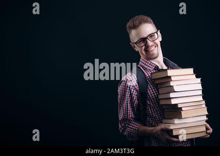 Lächelnden jungen Mann mit einem Stapel Bücher Stockfoto