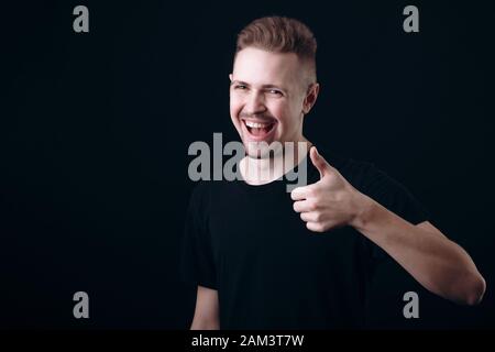 Ein lächelndes Bärtigen Youngster mit Daumen hoch Stockfoto