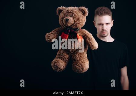 Verschwommen junger Mann mit einem Teddybären zu Kamera Stockfoto