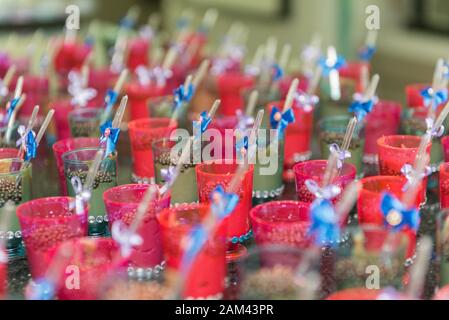 Nahaufnahme von transparenten Tassen mit Schokolade und Plastiklöffel mit blauem Bogen auf der Kinderparty. Selektiver Fokus. Stockfoto