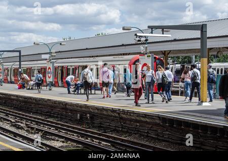 London, Großbritannien - 22. Juni 2019: Passagiere, die an einem sonnigen Sommertag auf einen District Line Zug am Ealing Broadway Station in West London warten. Stockfoto