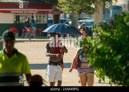 Coimbra, PORTUGAL - 16. Juli 2016 - EIN Mann verwendet einen Regenschirm, um sich während einer Hitzewelle in Coimbra Portugal kühl zu halten Stockfoto