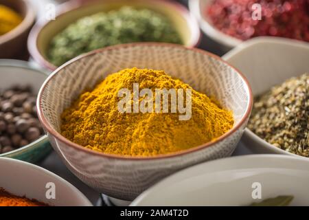 Curry und verschiedene Gewürze und Kräuter in Schüsseln Stockfoto