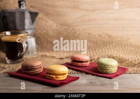 Traditionelle französische Makronen auf einem Holztisch mit einer Tasse Kaffee. Stockfoto