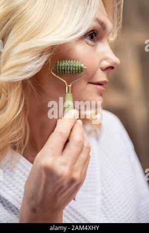 Gut aussehende Frau selbst eine Gesichtsmassage Stockfoto