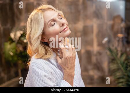 Schöne Dame Parfum sprühen an ihrem Hals Stockfoto