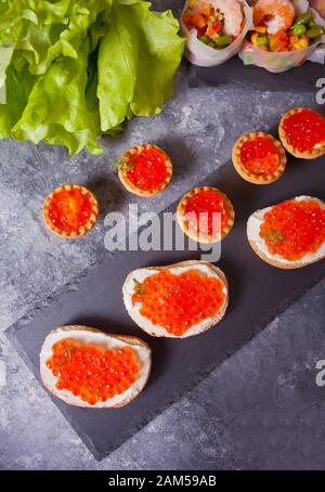 Frischer roter Kaviar auf Brot. Sandwiches mit rotem Kaviar und Tessel mit rotem Kaviar. Feinkost. Gourmetküche. Draufsicht. Stockfoto