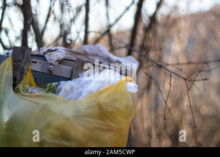 Überlaufene Mülltonne mit mehreren Müllsäcken um sie herum. Das Problem mit den Abfallstoffen, die Menschen verursachen, ist die Notwendigkeit von Recycling und Abfallwirtschaft. Stockfoto