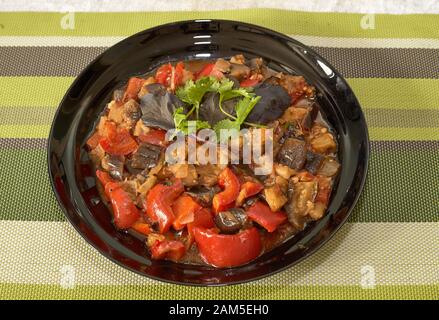 Roter Pfeffer mit Aubergine in eigener Sauce und Petersilienblatt darauf. Stockfoto