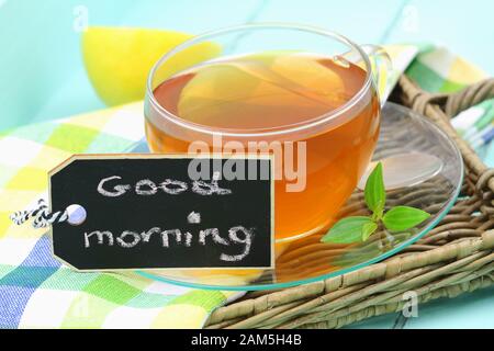 Guten Morgen auf Mini-Holzschwärze mit einer Tasse Zitronentee geschrieben Stockfoto