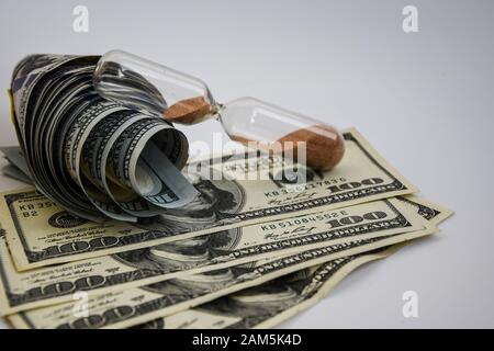 Zeit ist Geld, Rolle amerikanischer Dollar, Bargeld, Sandglas auf der weißen Rückseite mit Platz für Text Stockfoto