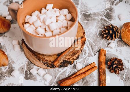 Eine Tasse köstlicher heißer Schokolade und Kakao mit Marshmallows mit Kakaopulver, Kegel und Croissants, Zimt in Grau Stockfoto