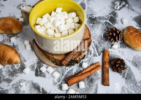 Eine Tasse köstlicher heißer Schokolade und Kakao mit Marshmallows mit Kakaopulver, Kegel und Croissants, Zimt in Grau Stockfoto