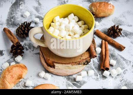 Eine Tasse köstlicher heißer Schokolade und Kakao mit Marshmallows mit Kakaopulver, Kegel und Croissants, Zimt in Grau Stockfoto