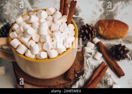 Eine Tasse köstlicher heißer Schokolade und Kakao mit Marshmallows mit Kakaopulver, Kegel und Croissants, Zimt in Grau Stockfoto