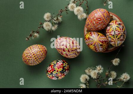 Pysanky, ukrainische Ostereier mit Wachsresistenten Färbetechniken dekoriert. Grüner Hintergrund mit trockenen Blumen Stockfoto