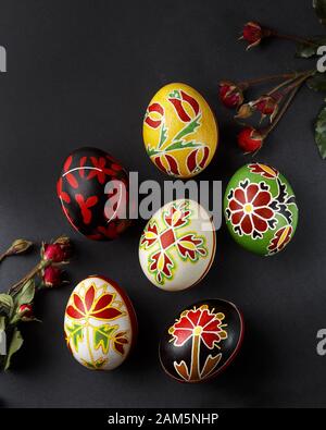 Pysanky, ukrainische Ostereier mit Wachsresistent Färbetechnik dekoriert, rote Rosen blühen auf schwarzem Grund Stockfoto