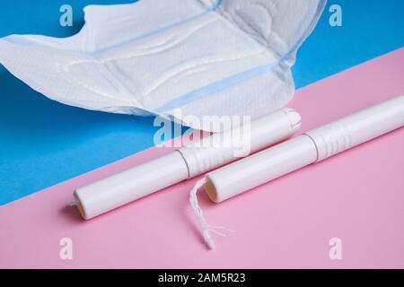 Hygienische Tampons und Pads auf blauem und rosafarbenem Hintergrund. Kopierbereich Stockfoto