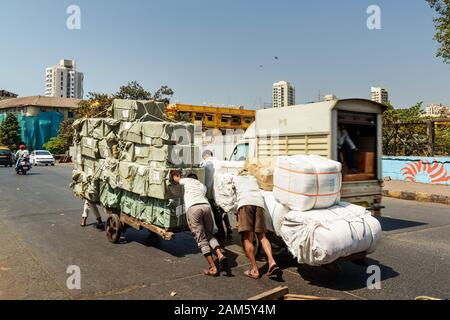 Männer drängten in Mumbai auf den Markt geladener Wagen. Indien Stockfoto