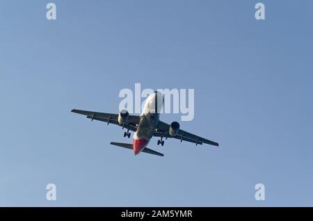 Niedriger Winkel des kommerziellen Flugzeuges gegen den Himmel, gezogene Landeausrüstung, kurz vor der Landung Stockfoto