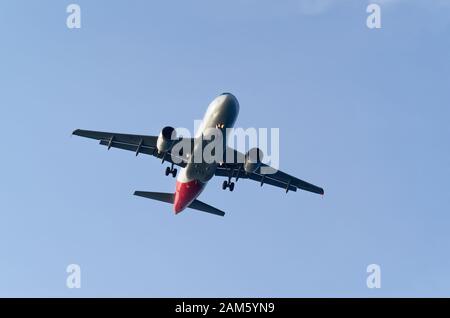 Niedriger Winkel des kommerziellen Flugzeuges gegen den Himmel, gezogene Landeausrüstung, kurz vor der Landung Stockfoto