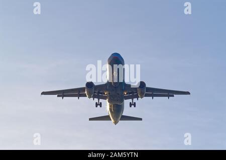 Niedriger Winkel des kommerziellen Flugzeuges gegen den Himmel, gezogene Landeausrüstung, kurz vor der Landung Stockfoto