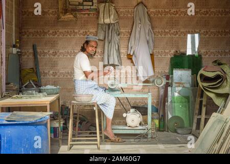 Der indische Mann schärft Steinstücke auf der Maschine in Dharavi Slum in Mumbai. Indien Stockfoto